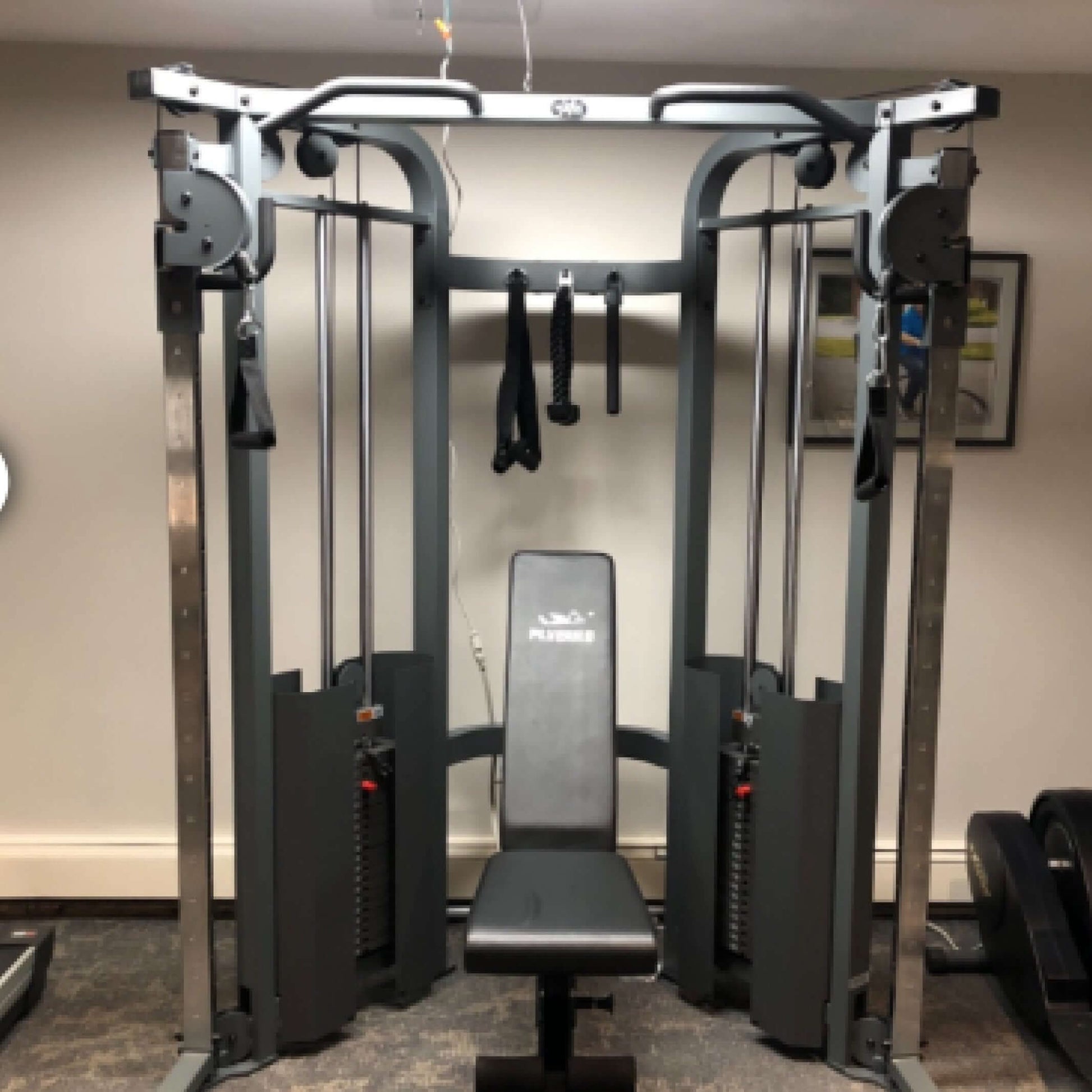 Functional trainer cable machine featuring adjustable weight stacks and bench for versatile workouts.